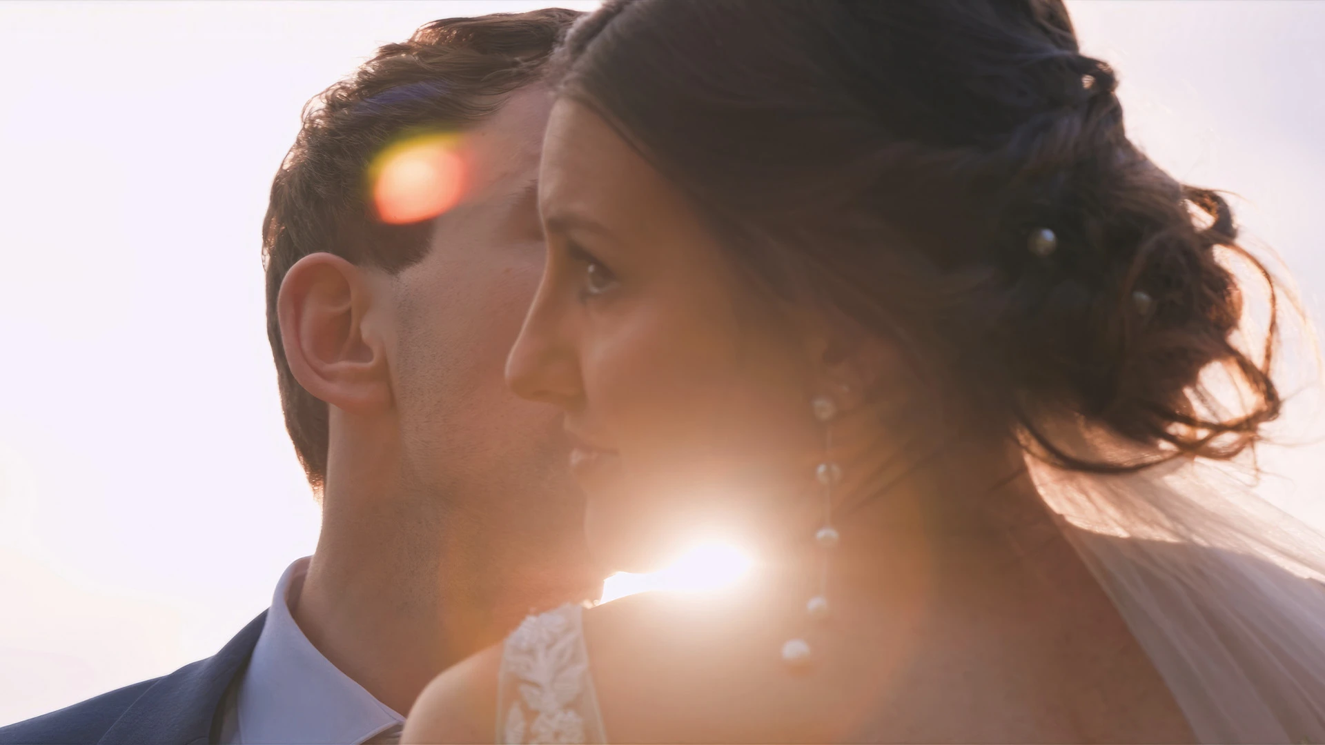 Alara and Chris close together with the sun flaring behind them at their Montana wedding