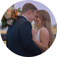 Anna and Alec laughing forehead to forehead at their Montana wedding, an autumn bouquet beside them
