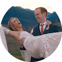 Carleigh and Eric laughing, one lifting the other, with Montana mountains behind them