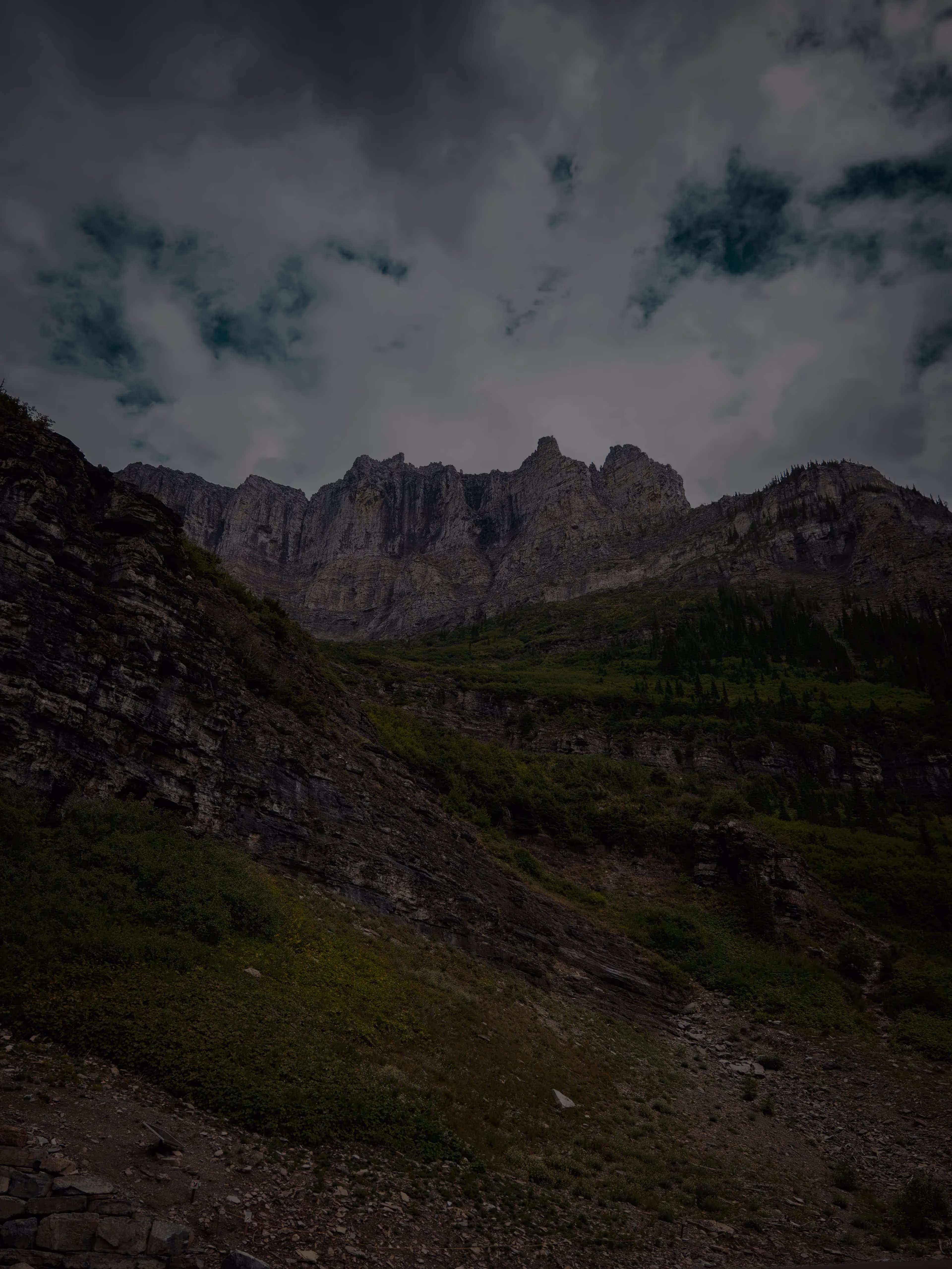 Moody clouds over rocky cliffs and mountain goats in Glacier National Park Montana