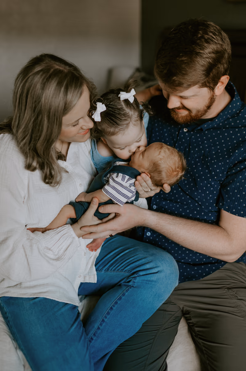 Skeeter Johnston and his wife holding their newborn son while their daughter leans in to kiss him
